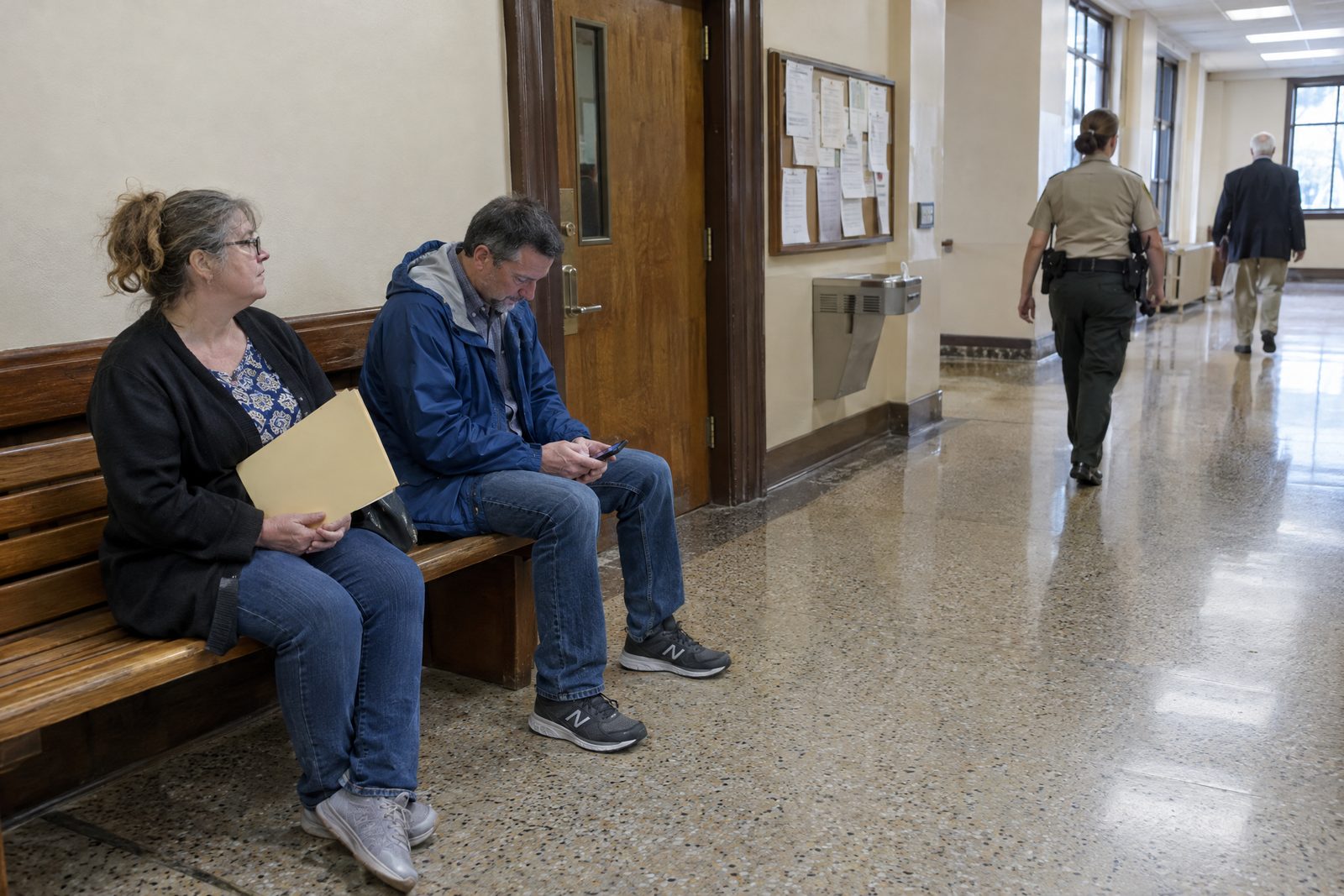 People waiting on a bench in a county courthouse hallway
